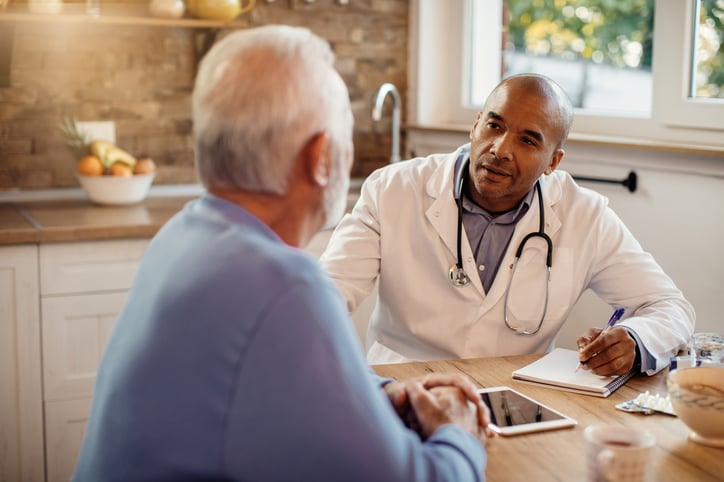 male-african-adult-doctor-talking-to-senior-man-while-visiting-him-at-home-print
